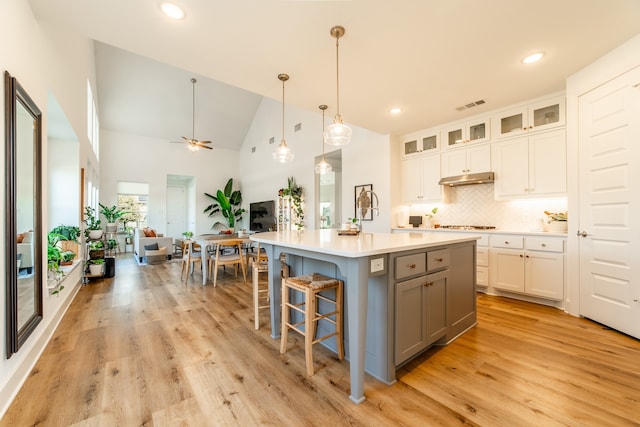 kitchen featuring white cabinets, light hardwood / wood-style flooring, ceiling fan, and an island with sink