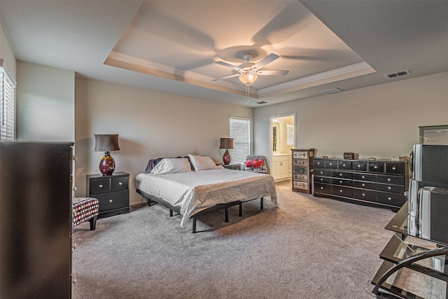 carpeted bedroom with a tray ceiling, ensuite bath, and ceiling fan