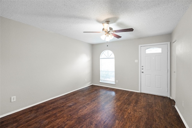 entryway featuring dark wood-type flooring, ceiling fan, and a textured ceiling