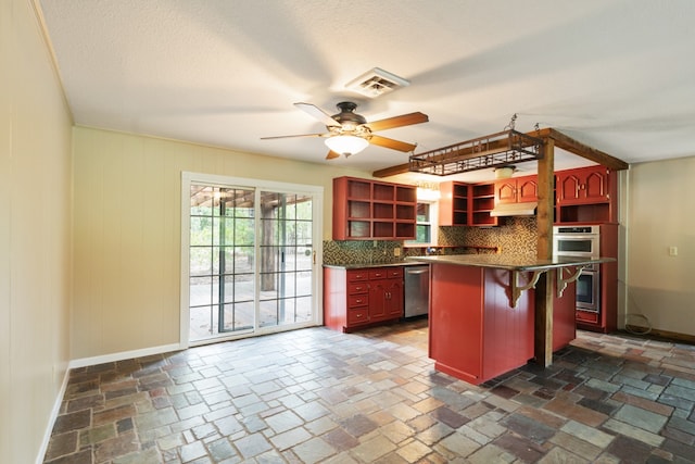 kitchen featuring ceiling fan, a center island, stainless steel appliances, a kitchen breakfast bar, and backsplash