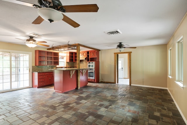 kitchen with a kitchen breakfast bar, a kitchen island, stainless steel double oven, and decorative backsplash