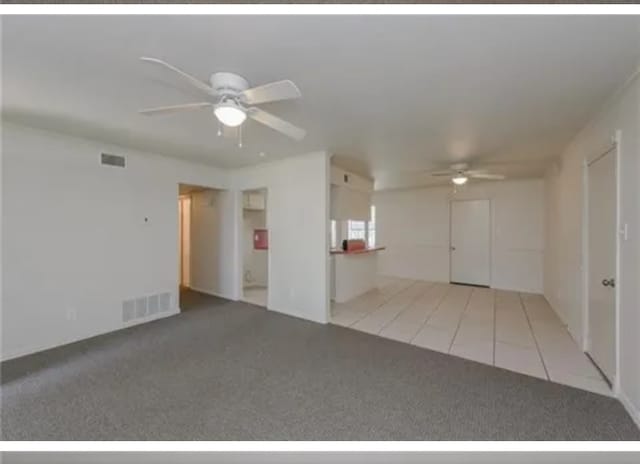 unfurnished living room with light colored carpet and ceiling fan