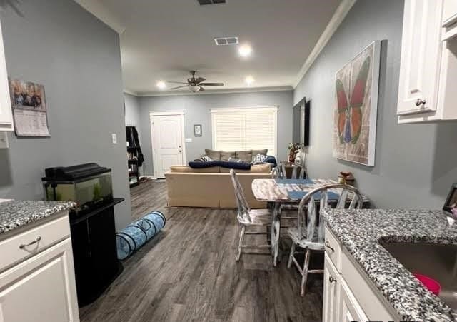 kitchen with dark hardwood / wood-style floors, stone countertops, crown molding, ceiling fan, and white cabinets