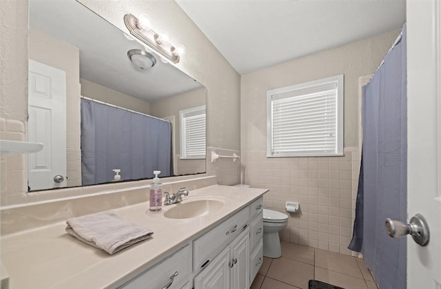 bathroom with vanity, walk in shower, tile patterned flooring, tile walls, and toilet