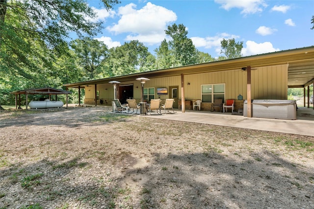 rear view of property with a hot tub and a patio