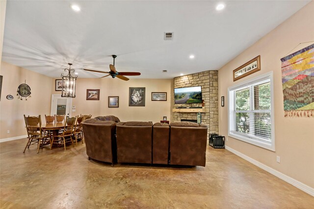 living room featuring ceiling fan with notable chandelier and a stone fireplace