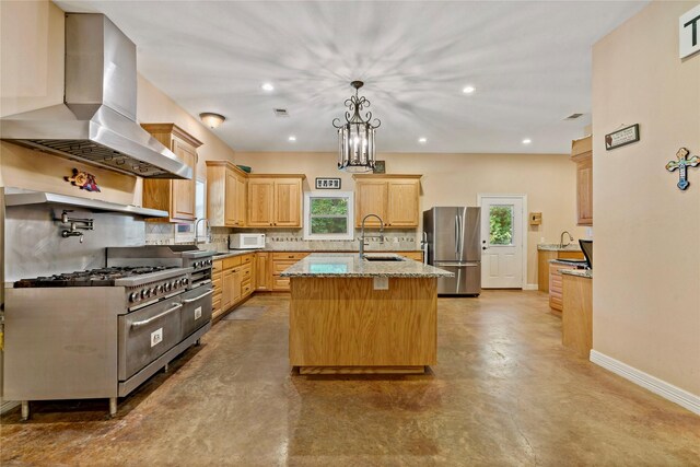 kitchen featuring wall chimney exhaust hood, appliances with stainless steel finishes, a healthy amount of sunlight, and a center island with sink