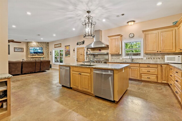 kitchen featuring dishwasher, ceiling fan with notable chandelier, light brown cabinets, decorative backsplash, and a center island with sink