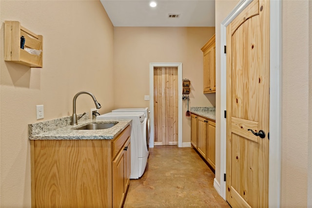 kitchen with light stone counters, sink, independent washer and dryer, and light brown cabinetry