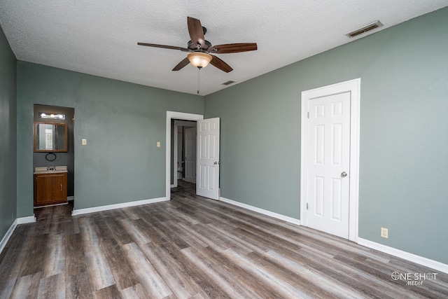 empty room featuring dark hardwood / wood-style flooring, ceiling fan, and a textured ceiling