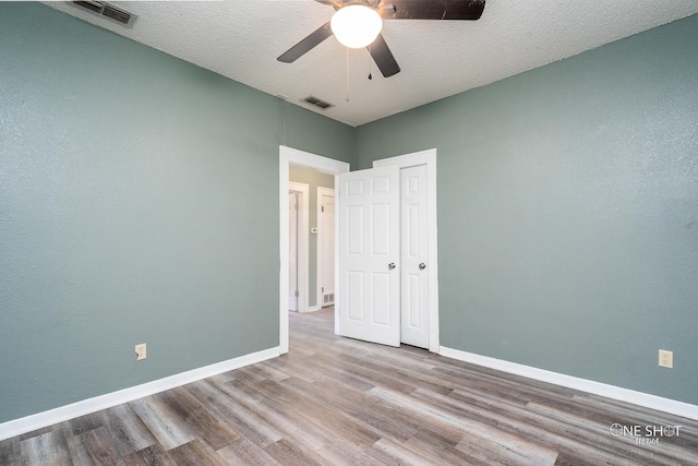 spare room featuring a textured ceiling, hardwood / wood-style flooring, and ceiling fan