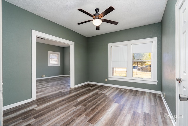 empty room featuring dark wood-type flooring, a textured ceiling, and ceiling fan