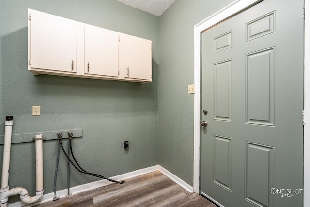 washroom featuring hookup for a washing machine, cabinets, wood-type flooring, and a textured ceiling