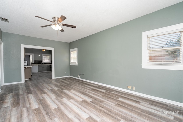 unfurnished room featuring a textured ceiling, light hardwood / wood-style flooring, and ceiling fan