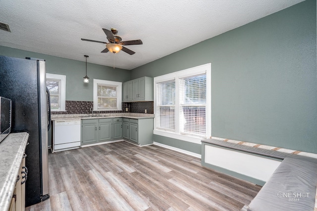 kitchen featuring backsplash, dishwasher, sink, ceiling fan, and light hardwood / wood-style floors