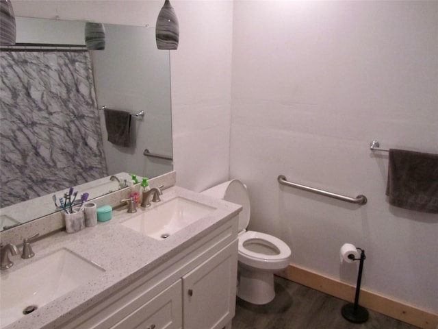 full bath featuring double vanity, wood finished floors, toilet, and a sink