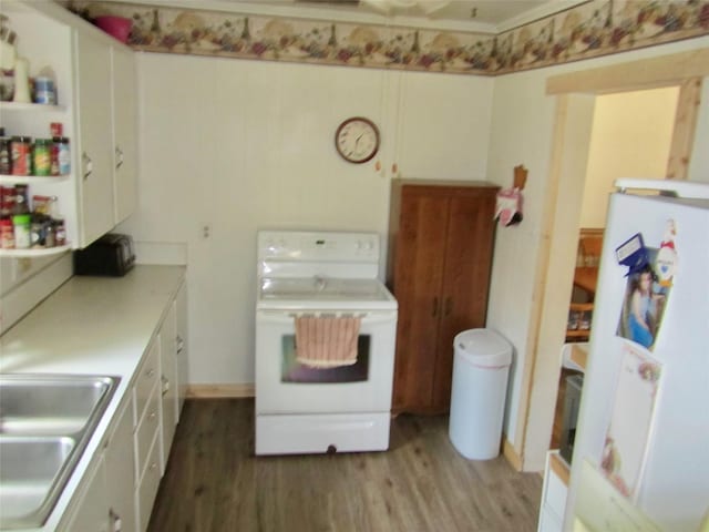 kitchen with a sink, white appliances, light wood-style floors, white cabinets, and light countertops