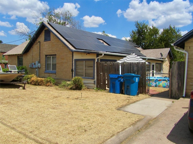 view of side of home featuring a gate, stone siding, solar panels, and fence