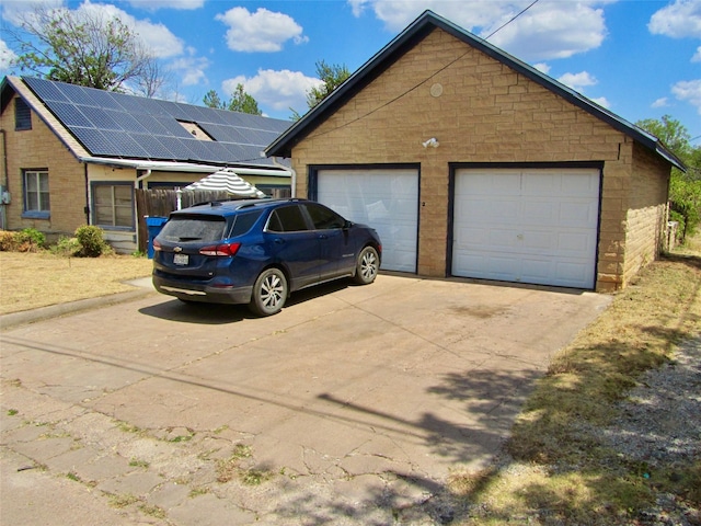 exterior space with roof mounted solar panels and a garage