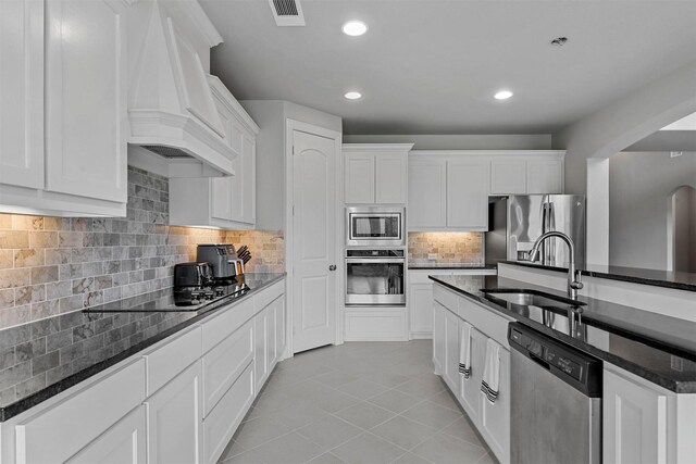 kitchen with light tile patterned floors, backsplash, stainless steel appliances, sink, and white cabinetry