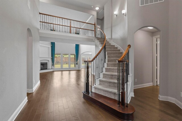 stairs with a towering ceiling and wood-type flooring