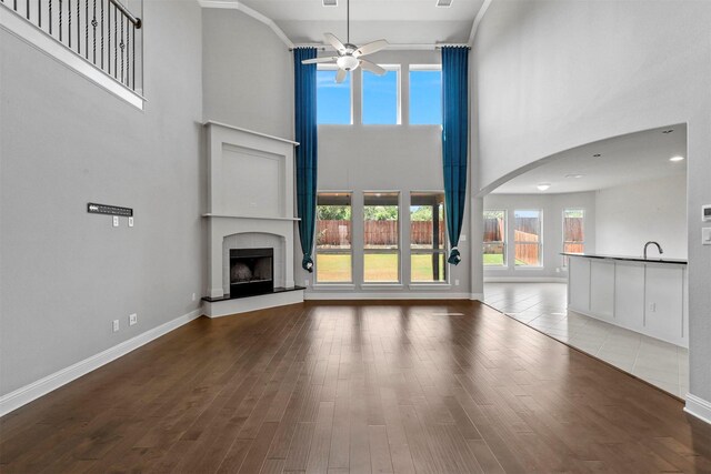 unfurnished living room with ceiling fan, hardwood / wood-style flooring, and a towering ceiling