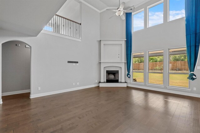 unfurnished living room featuring a wealth of natural light, ceiling fan, dark hardwood / wood-style floors, and high vaulted ceiling