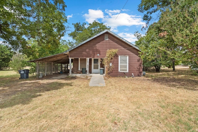 back of house featuring a lawn and a carport