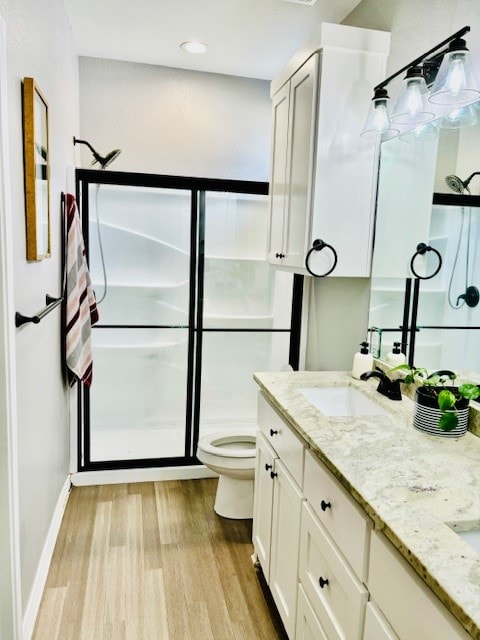 bathroom featuring vanity, toilet, hardwood / wood-style flooring, and an enclosed shower