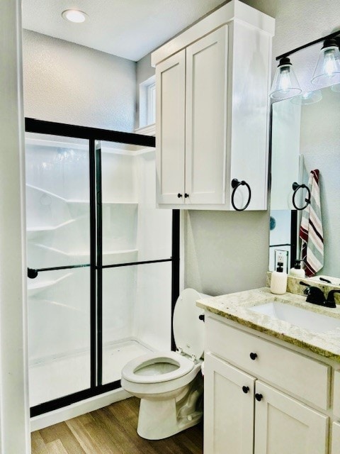 bathroom featuring vanity, toilet, hardwood / wood-style floors, and a shower with shower door