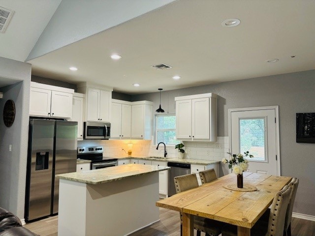 kitchen with appliances with stainless steel finishes, tasteful backsplash, a wealth of natural light, and hanging light fixtures