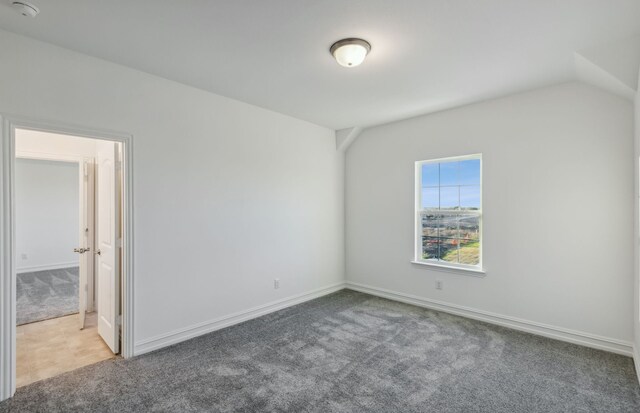 carpeted empty room featuring vaulted ceiling