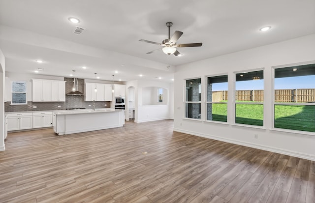 unfurnished living room featuring light wood-type flooring, ceiling fan, and sink