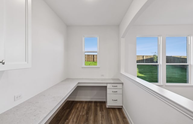 unfurnished office featuring dark hardwood / wood-style flooring and built in desk