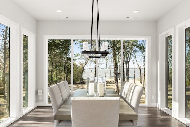 unfurnished dining area featuring a water view, dark wood-type flooring, and a notable chandelier