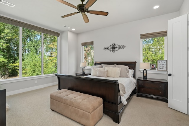 bedroom featuring ceiling fan, light colored carpet, and multiple windows