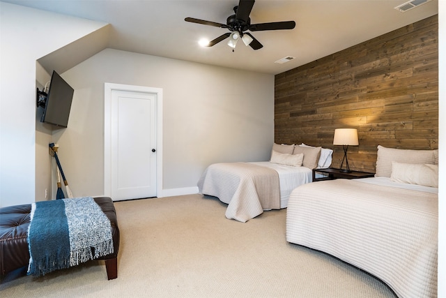 carpeted bedroom with wooden walls and ceiling fan