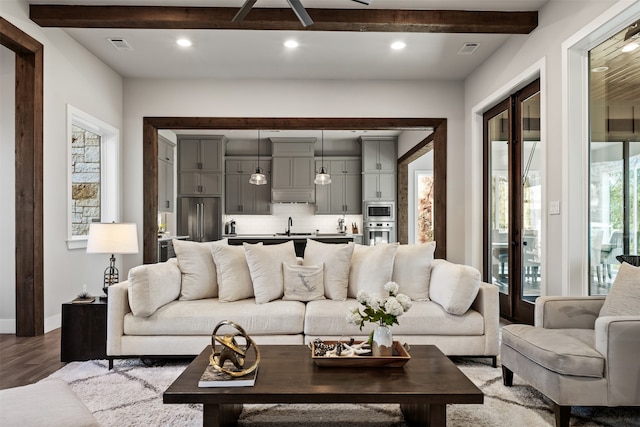 living room featuring beam ceiling, sink, and hardwood / wood-style flooring