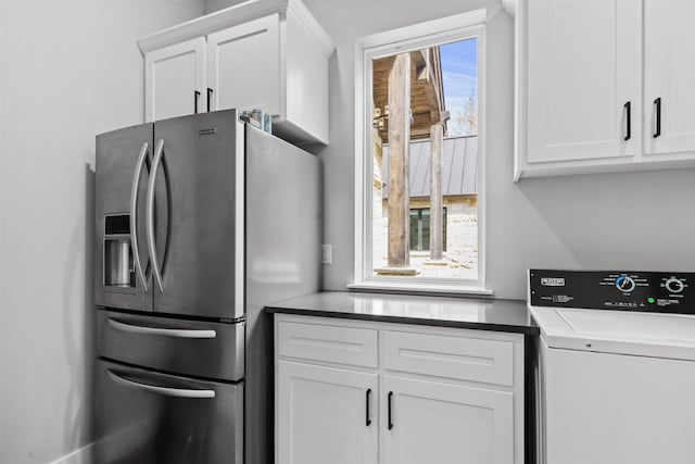 kitchen with white cabinets, washer / dryer, and stainless steel fridge