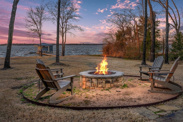 yard at dusk with a fire pit and a water view