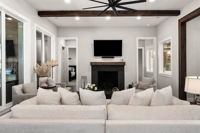 living room featuring ceiling fan, a fireplace, and beam ceiling