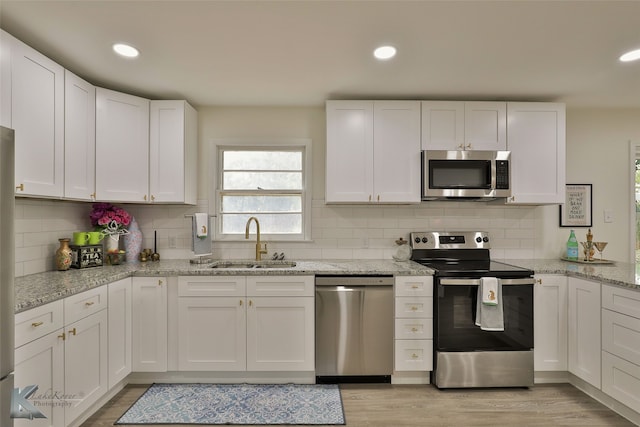 kitchen featuring white cabinets, appliances with stainless steel finishes, light hardwood / wood-style floors, and sink