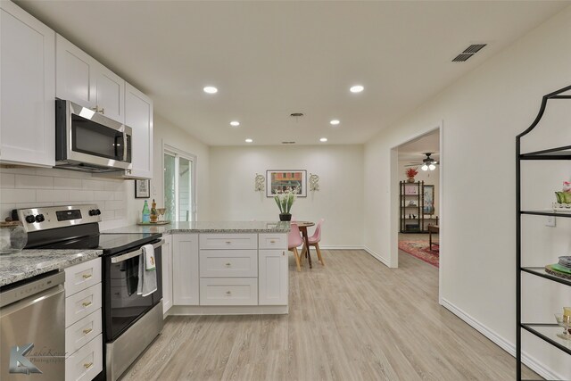 kitchen featuring white cabinets, appliances with stainless steel finishes, light stone countertops, and light hardwood / wood-style flooring