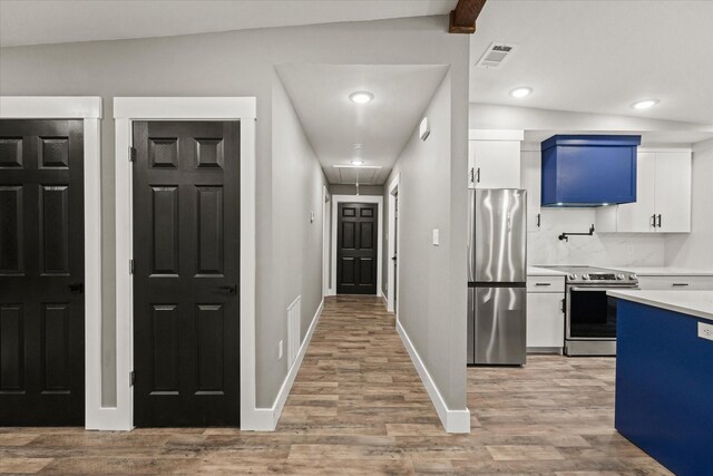 kitchen featuring light hardwood / wood-style flooring, stainless steel appliances, vaulted ceiling, and white cabinets