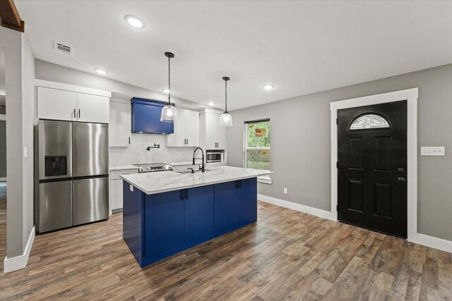 kitchen featuring stainless steel appliances, white cabinetry, dark wood-type flooring, decorative backsplash, and a kitchen island with sink