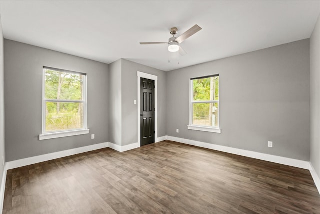 spare room with a healthy amount of sunlight, ceiling fan, and dark hardwood / wood-style flooring