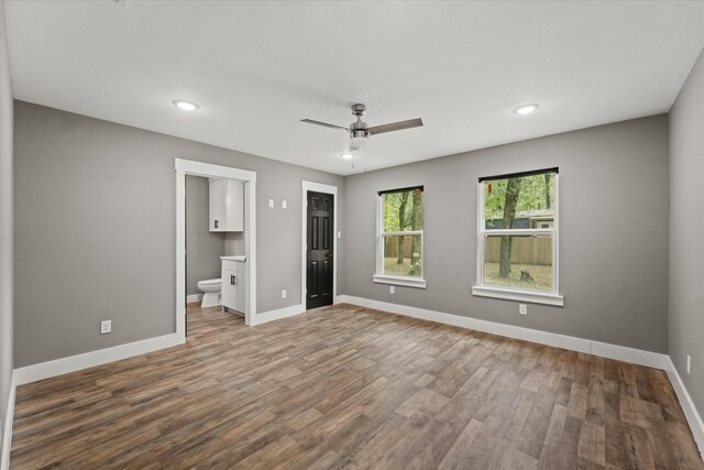 unfurnished bedroom featuring hardwood / wood-style floors, ceiling fan, and connected bathroom