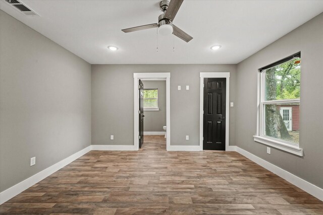 unfurnished bedroom featuring ceiling fan, ensuite bath, and wood-type flooring