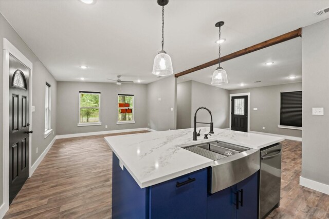 kitchen featuring decorative light fixtures, dark hardwood / wood-style flooring, sink, blue cabinets, and a kitchen island with sink