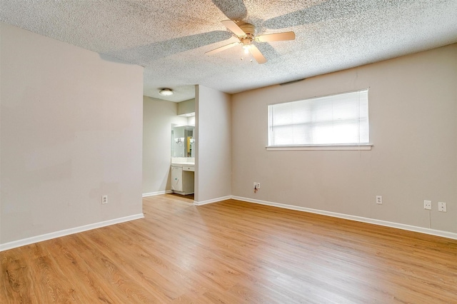 spare room featuring light wood-style floors, ceiling fan, baseboards, and a textured ceiling